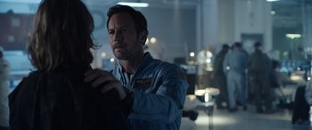 Movie still from “Moonfall” (2022), directed by Roland Emmerich – A man standing in a room holding a woman's hand; Medium shot, Over the shoulder angle