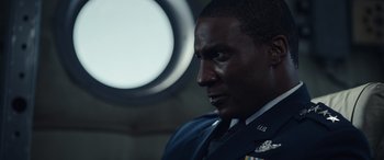Movie still from “Moonfall” (2022), directed by Roland Emmerich – A person wearing a military uniform; Close Up shot, Over the shoulder angle