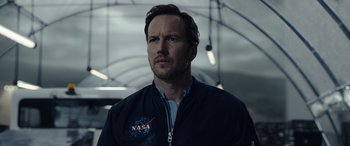 Movie still from “Moonfall” (2022), directed by Roland Emmerich – A man wearing a nasa jacket standing in a tunnel; Close Up shot, Over the shoulder angle