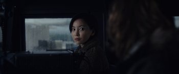 Movie still from “Moonfall” (2022), directed by Roland Emmerich – A woman is standing in the rain on a bus; Close Up shot, Over the shoulder angle