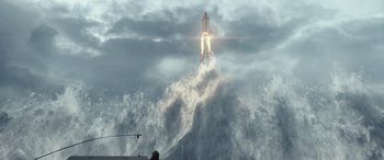 Movie still from “Moonfall” (2022), directed by Roland Emmerich – A rocket is flying through the air while a man watches from a boat; Extreme Wide shot, Low angle