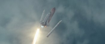 Movie still from “Moonfall” (2022), directed by Roland Emmerich – A space ship is flying in the air with a rocket in the background; Extreme Wide shot, Low angle