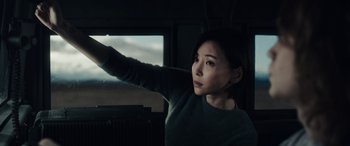 Movie still from “Moonfall” (2022), directed by Roland Emmerich – A woman in a green sweater holding onto a window; Medium shot, High angle