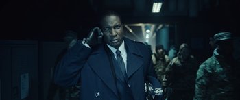 Movie still from “Moonfall” (2022), directed by Roland Emmerich – A man wearing a suit and tie holding a cell phone; Close Up shot, Low angle