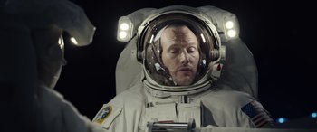 Movie still from “Moonfall” (2022), directed by Roland Emmerich – A man in a spacesuit is looking into a mirror; Close Up shot, Overhead angle