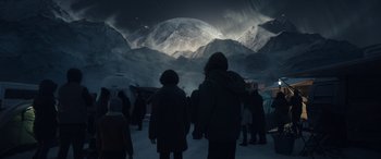 Movie still from “Moonfall” (2022), directed by Roland Emmerich – A group of people standing in front of a mountain at night; Extreme Wide shot, Low angle