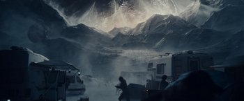 Movie still from “Moonfall” (2022), directed by Roland Emmerich – A man riding a motorcycle through a snow covered mountain range; Extreme Wide shot, High angle