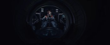 Movie still from “Moonfall” (2022), directed by Roland Emmerich – A man in a space suit is sitting in the cockpit of an aircraft; Wide shot, Overhead angle