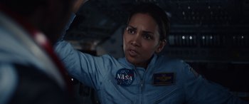 Movie still from “Moonfall” (2022), directed by Roland Emmerich – A woman in a nasa uniform is looking at the camera; Close Up shot, Overhead angle