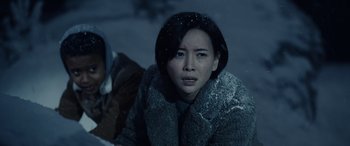 Movie still from “Moonfall” (2022), directed by Roland Emmerich – A woman in a fur coat sitting in the snow; Close Up shot, High angle