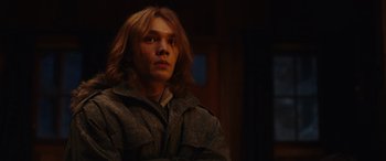 Movie still from “Moonfall” (2022), directed by Roland Emmerich – A man with long blonde hair wearing a jacket; Close Up shot, Low angle