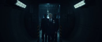 Movie still from “Moonfall” (2022), directed by Roland Emmerich – A group of men standing next to each other in a dark room; Medium shot, Low angle