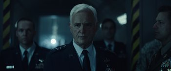 Movie still from “Moonfall” (2022), directed by Roland Emmerich – An older man in a military uniform stands next to another man in a suit and tie; Close Up shot, Low angle