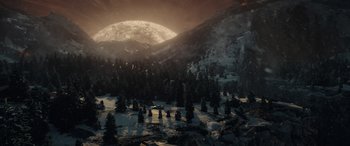 Movie still from “Moonfall” (2022), directed by Roland Emmerich – A full moon setting over a snowy mountain; Extreme Wide shot, High angle