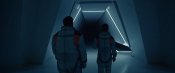 Movie still from “Moonfall” (2022), directed by Roland Emmerich – Two people are walking down a dark hallway; Wide shot, High angle
