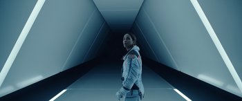 Movie still from “Moonfall” (2022), directed by Roland Emmerich – A woman standing in an empty room wearing a space suit; Medium shot, Low angle