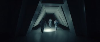 Movie still from “Moonfall” (2022), directed by Roland Emmerich – Three people in spacesuits walking down a tunnel; Wide shot, Overhead angle