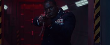 Movie still from “Moonfall” (2022), directed by Roland Emmerich – A man in a military uniform is holding a gun; Medium shot, Low angle