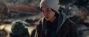 Movie still from “Moonfall” (2022), directed by Roland Emmerich – A woman wearing a white hat and a brown coat; Close Up shot, Over the shoulder angle