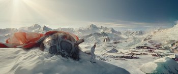 Movie still from “Moonfall” (2022), directed by Roland Emmerich – A man in a white suit standing in the snow near an abandoned car; Extreme Wide shot, High angle