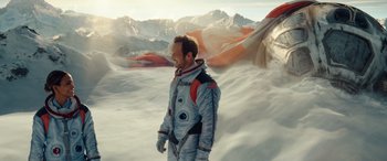 Movie still from “Moonfall” (2022), directed by Roland Emmerich – A man in a spacesuit standing in the middle of a snowy field; Wide shot, Overhead angle