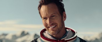 Movie still from “Moonfall” (2022), directed by Roland Emmerich – A person wearing a space suit smiling; Close Up shot, Overhead angle