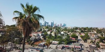 Movie still from “More Than Robots” (2022), directed by Gillian Jacobs – A view of a city from a hill with palm trees; Extreme Wide shot, Low angle