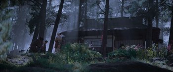 Movie still from “Mortal Kombat” (2021), directed by Simon McQuoid – A person standing in the woods near a house; Extreme Wide shot, Low angle