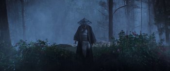 Movie still from “Mortal Kombat” (2021), directed by Simon McQuoid – A man in a hat and armor standing in the woods; Wide shot, Low angle