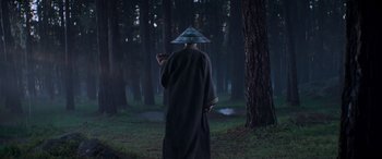 Movie still from “Mortal Kombat” (2021), directed by Simon McQuoid – A man in a hat standing in the middle of a forest; Wide shot, Low angle