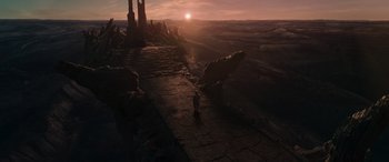 Movie still from “Mortal Kombat” (2021), directed by Simon McQuoid – The sun is setting over the mountains with a person standing on the steps; Extreme Wide shot, High angle