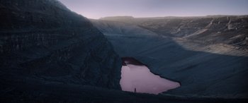Movie still from “Mortal Kombat” (2021), directed by Simon McQuoid – A person standing on top of a mountain next to a lake; Extreme Wide shot, High angle