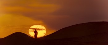 Movie still from “Mortal Kombat” (2021), directed by Simon McQuoid – A person standing on top of a hill at sunset; Extreme Wide shot, Low angle