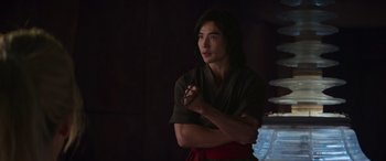 Movie still from “Mortal Kombat” (2021), directed by Simon McQuoid – A young man in a robe is holding a rosary; Medium shot, Over the shoulder angle