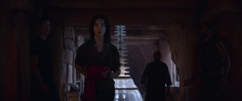 Movie still from “Mortal Kombat” (2021), directed by Simon McQuoid – A man standing in a dark room with a red tie; Medium shot, Low angle