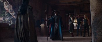 Movie still from “Mortal Kombat” (2021), directed by Simon McQuoid – A man wearing a hat and holding a staff; Wide shot, Over the shoulder angle