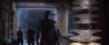 Movie still from “Mortal Kombat” (2021), directed by Simon McQuoid – A man wearing a hat and a black outfit; Medium shot, Over the shoulder angle