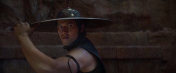 Movie still from “Mortal Kombat” (2021), directed by Simon McQuoid – A man wearing a hat is holding a sword; Close Up shot, Over the shoulder angle