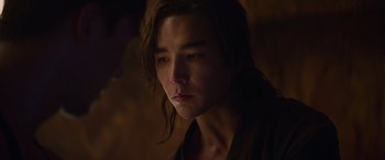Movie still from “Mortal Kombat” (2021), directed by Simon McQuoid – A man with long brown hair is looking at the camera; Close Up shot, Over the shoulder angle