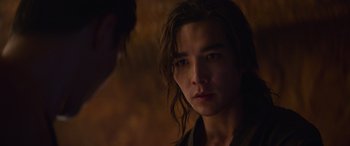 Movie still from “Mortal Kombat” (2021), directed by Simon McQuoid – A man with long brown hair stares into the camera; Close Up shot, Over the shoulder angle