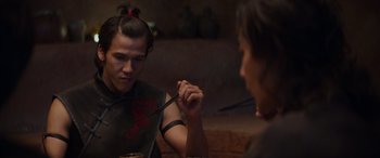Movie still from “Mortal Kombat” (2021), directed by Simon McQuoid – A man holding a fork in his hand while another man holds a spoon; Close Up shot, Over the shoulder angle