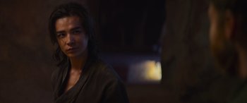 Movie still from “Mortal Kombat” (2021), directed by Simon McQuoid – A man with long black hair standing in a dark room; Close Up shot, Over the shoulder angle