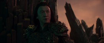Movie still from “Mortal Kombat” (2021), directed by Simon McQuoid – A man with a long black hair wearing a green and black outfit; Close Up shot, Low angle