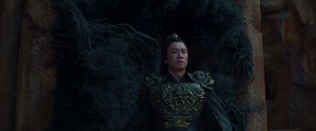 Movie still from “Mortal Kombat” (2021), directed by Simon McQuoid – A man in a black and gold outfit standing in front of a rock wall; Medium shot, Low angle