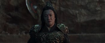 Movie still from “Mortal Kombat” (2021), directed by Simon McQuoid – An asian man in a black and gold outfit; Close Up shot, High angle