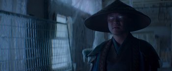 Movie still from “Mortal Kombat” (2021), directed by Simon McQuoid – A person wearing a hat standing next to a cage; Close Up shot, Low angle