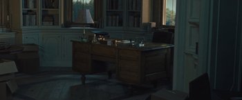 Movie still from “Mother!” (2017), directed by Darren Aronofsky – An empty desk in a dark room with a lamp on; Wide shot, High angle
