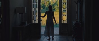 Movie still from “Mother!” (2017), directed by Darren Aronofsky – A woman standing in front of an open door; Wide shot, Low angle