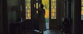Movie still from “Mother!” (2017), directed by Darren Aronofsky – A woman in a white dress standing in front of an open door; Wide shot, Low angle