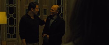 Movie still from “Mother!” (2017), directed by Darren Aronofsky – Two men are shaking hands in front of a building; Medium shot, Over the shoulder angle